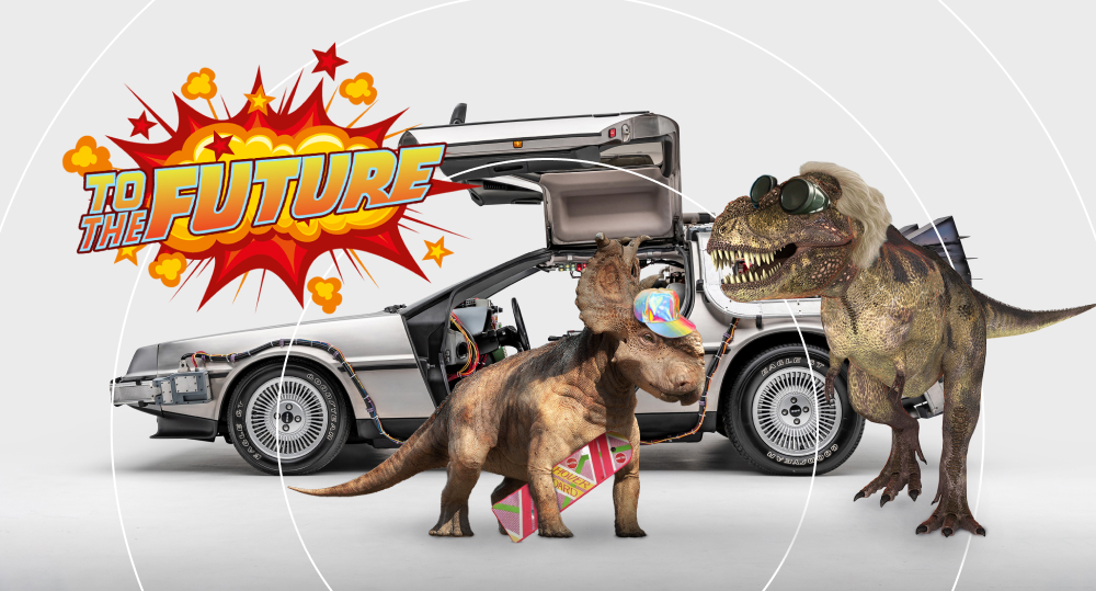 Two dinosaurs stand next to DeLorean DMC-12 with sign “To the Future!”