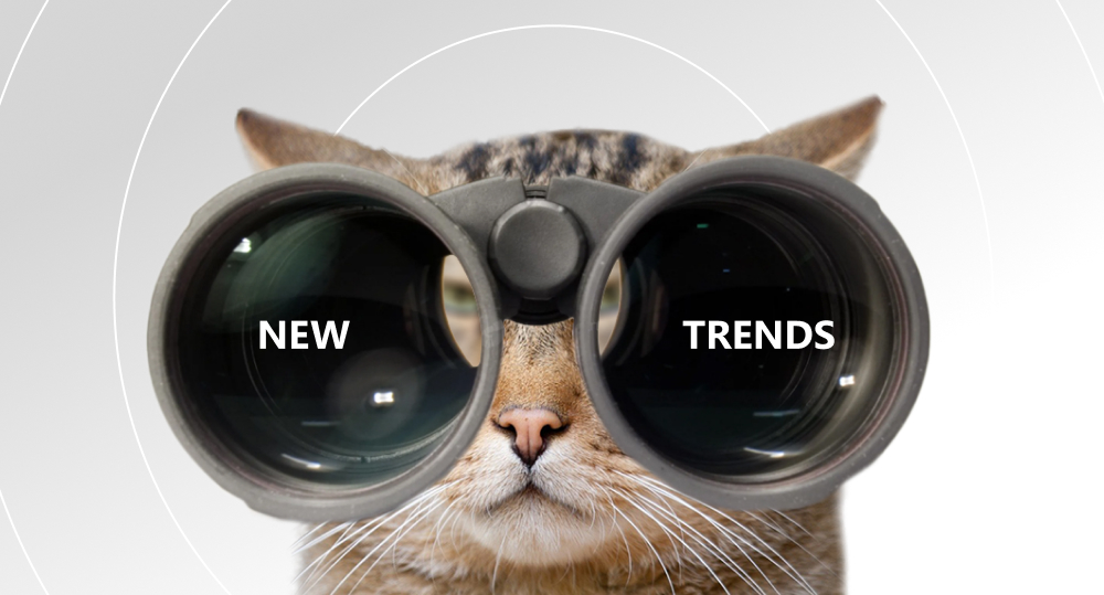 Cat looking through binoculars with words "new trends" written on the lens